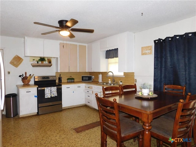 kitchen featuring stainless steel range with electric cooktop, white cabinets, sink, ceiling fan, and tasteful backsplash