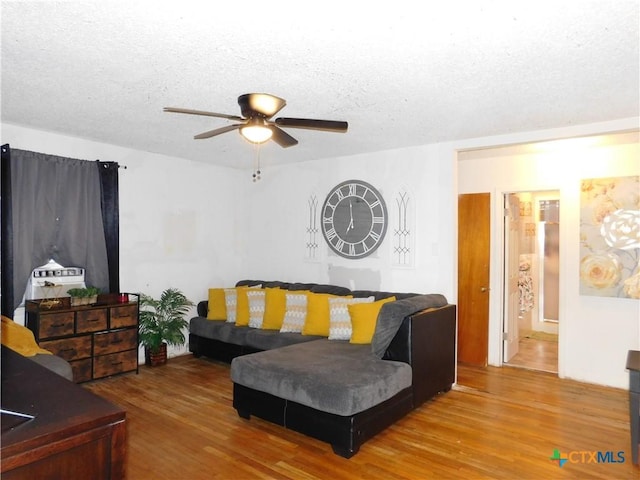 living room with hardwood / wood-style floors, a textured ceiling, and ceiling fan