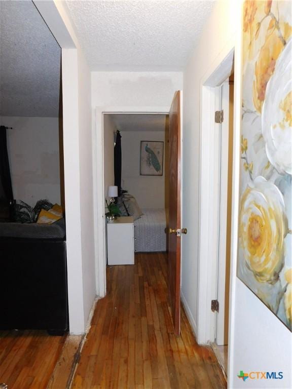 hall with hardwood / wood-style floors and a textured ceiling