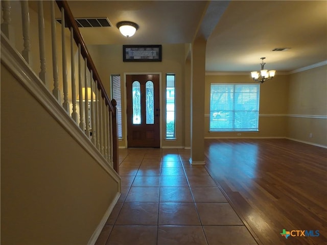 foyer featuring ornamental molding, dark tile patterned flooring, and an inviting chandelier