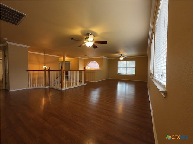 interior space with ceiling fan with notable chandelier, ornamental molding, and dark wood-type flooring