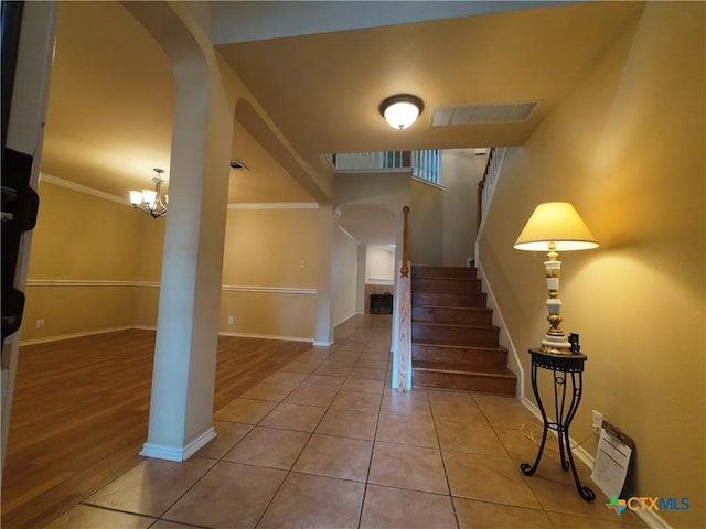 entrance foyer with light tile patterned floors, crown molding, and an inviting chandelier