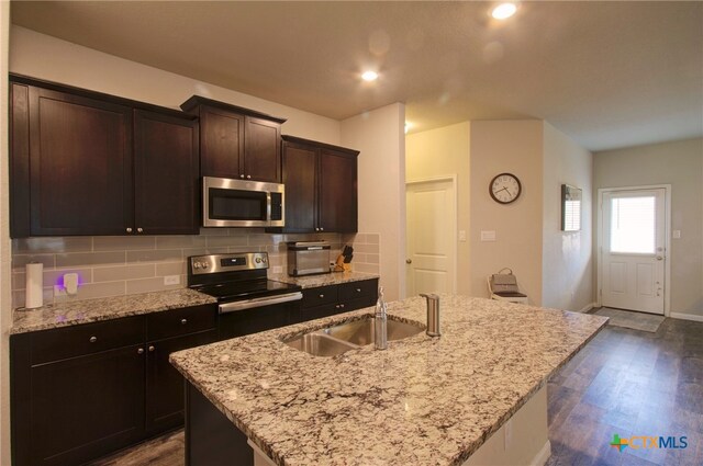 kitchen featuring dark hardwood / wood-style flooring, sink, a center island with sink, and stainless steel appliances