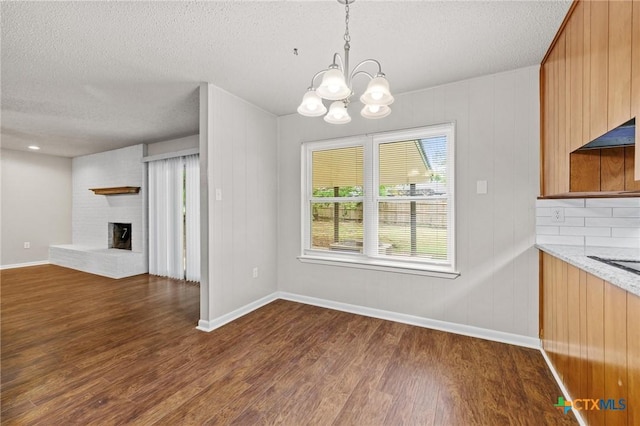 906 Laurie Ln, Copperas Cove, TX 76522 - unfurnished dining area with a textured ceiling, dark wood-type flooring, a chandelier, and a fireplace