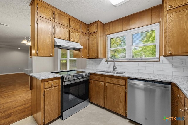 906 Laurie Ln, Copperas Cove, TX 76522 - kitchen featuring stainless steel appliances, under cabinet range hood, brown cabinets, and a textured ceiling