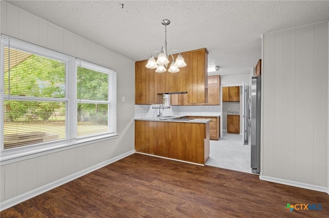 906 Laurie Ln, Copperas Cove, TX 76522 - kitchen with brown cabinets, a chandelier, dark wood finished floors, freestanding refrigerator, and a textured ceiling