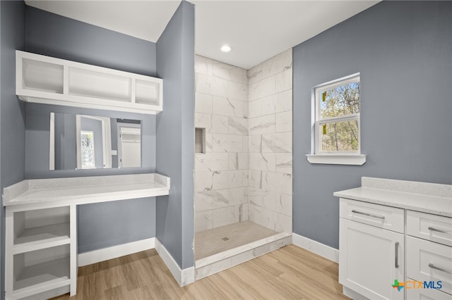 bathroom featuring hardwood / wood-style floors, vanity, and tiled shower