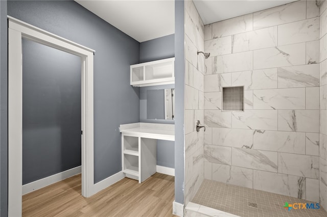 bathroom featuring wood-type flooring and a tile shower