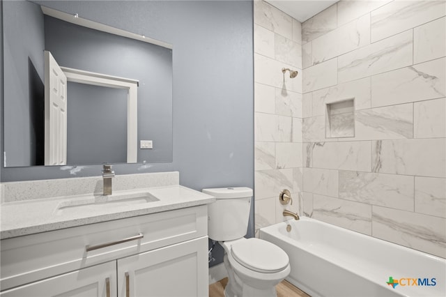 full bathroom featuring vanity, wood-type flooring, tiled shower / bath combo, and toilet