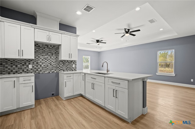 kitchen featuring a raised ceiling, white cabinets, and a healthy amount of sunlight