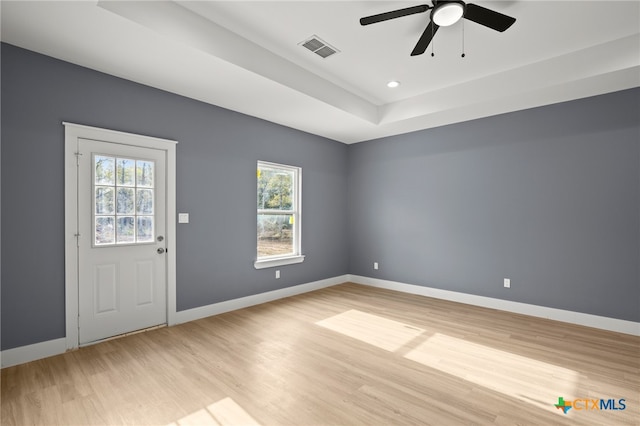 interior space featuring a raised ceiling, ceiling fan, and light hardwood / wood-style flooring