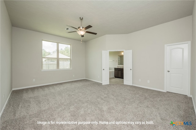 unfurnished bedroom featuring a textured ceiling, light colored carpet, ceiling fan, and connected bathroom