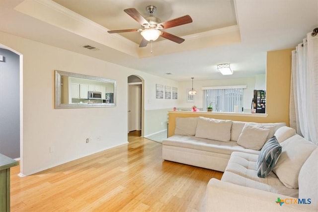 216 Pullman Place Blvd, Temple, TX 76502 - living area featuring a tray ceiling, arched walkways, light wood finished floors, a ceiling fan, and baseboards