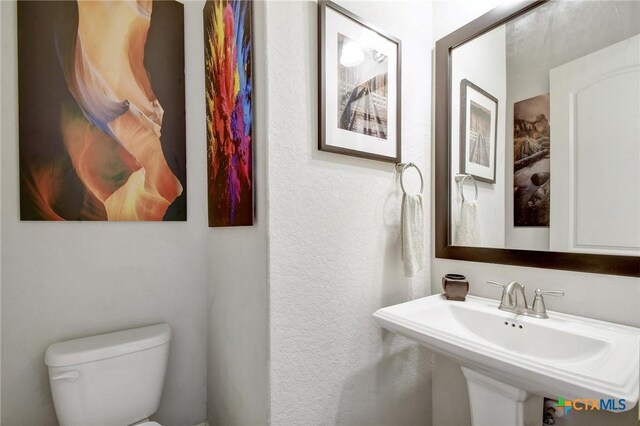 1812 Gibraltar Dr, San Marcos, TX 78666 - half bathroom featuring toilet, a sink, and a textured wall
