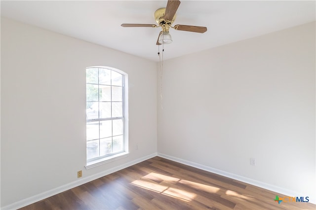 spare room with ceiling fan, a healthy amount of sunlight, and dark hardwood / wood-style flooring