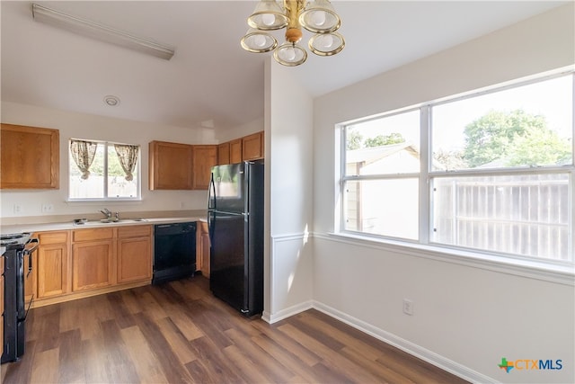 kitchen featuring dark wood-type flooring, sink, black appliances, and a notable chandelier