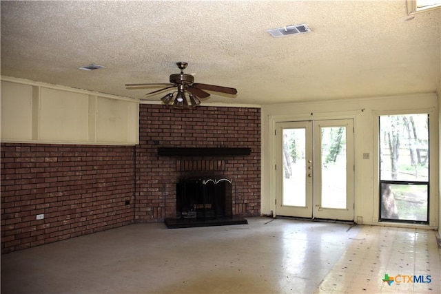765 Benchmark Trl, Belton, TX 76513 - unfurnished living room featuring a textured ceiling, a brick fireplace, brick wall, a ceiling fan, and french doors