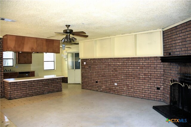 765 Benchmark Trl, Belton, TX 76513 - unfurnished living room with brick wall, ceiling fan, a textured ceiling, and a brick fireplace