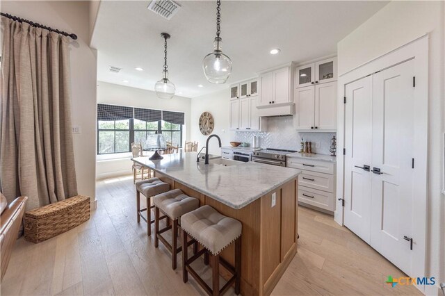 150 Panorama Dr, Wimberley, TX 78676 - kitchen with recessed lighting, light wood-type flooring, a breakfast bar, backsplash, and an island with sink