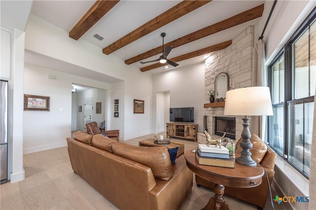 150 Panorama Dr, Wimberley, TX 78676 - living area featuring a stone fireplace, a ceiling fan, beam ceiling, and light wood finished floors