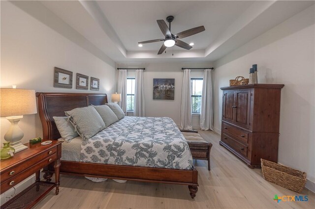 150 Panorama Dr, Wimberley, TX 78676 - bedroom with light wood finished floors, a raised ceiling, and a ceiling fan
