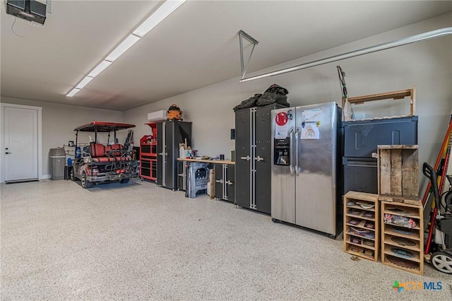 garage featuring stainless steel refrigerator with ice dispenser and a garage door opener