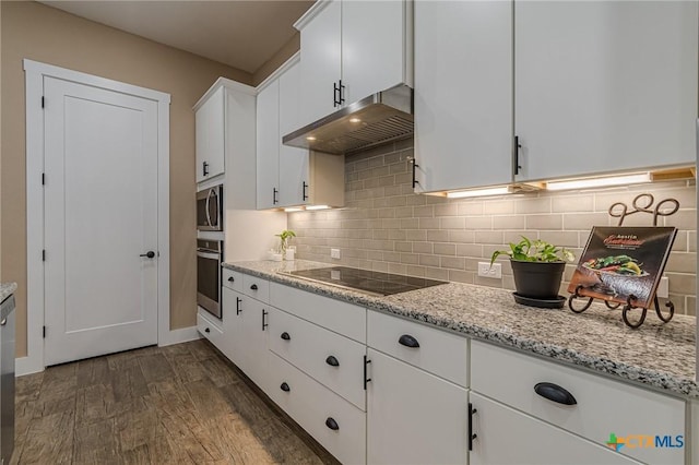 kitchen with decorative backsplash, light stone counters, stainless steel appliances, dark wood-type flooring, and white cabinets