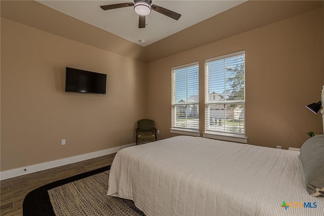 bedroom featuring multiple windows, ceiling fan, dark wood-type flooring, and vaulted ceiling