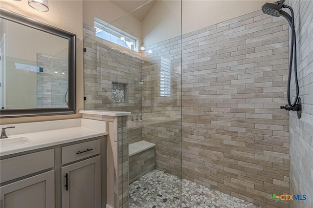 bathroom with a tile shower and vanity