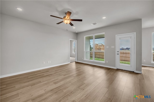 empty room with ceiling fan and light hardwood / wood-style flooring