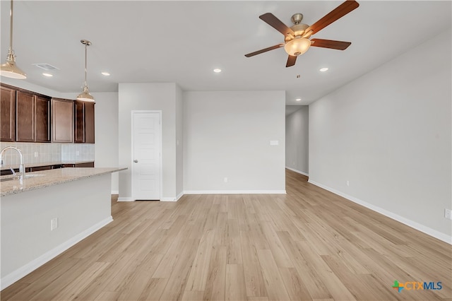 unfurnished living room featuring ceiling fan, sink, and light hardwood / wood-style floors