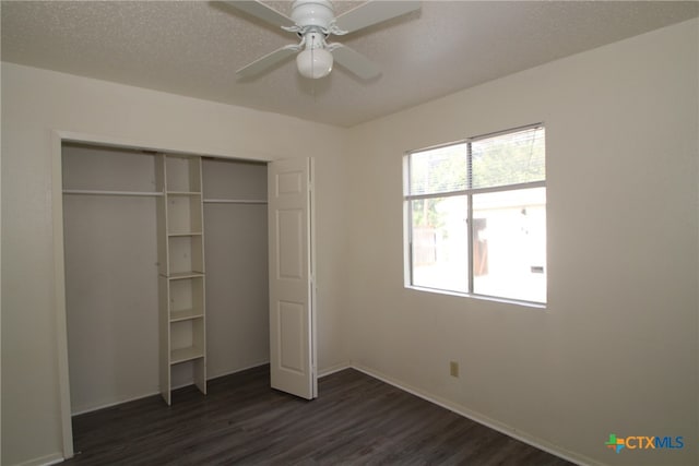 unfurnished bedroom with ceiling fan, a closet, dark wood-type flooring, and a textured ceiling