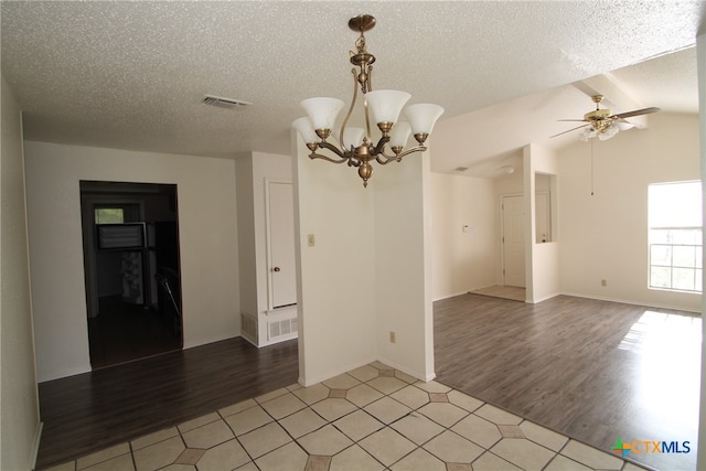 empty room featuring vaulted ceiling, ceiling fan with notable chandelier, a textured ceiling, and light wood-type flooring