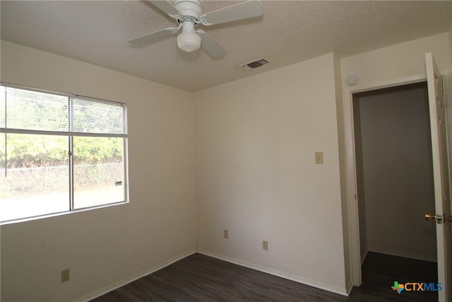 empty room featuring ceiling fan, dark wood-type flooring, and a textured ceiling