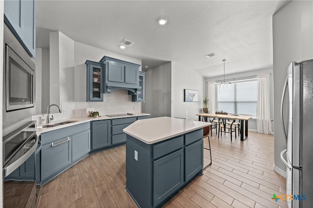 kitchen with pendant lighting, a center island, stainless steel appliances, tasteful backsplash, and sink