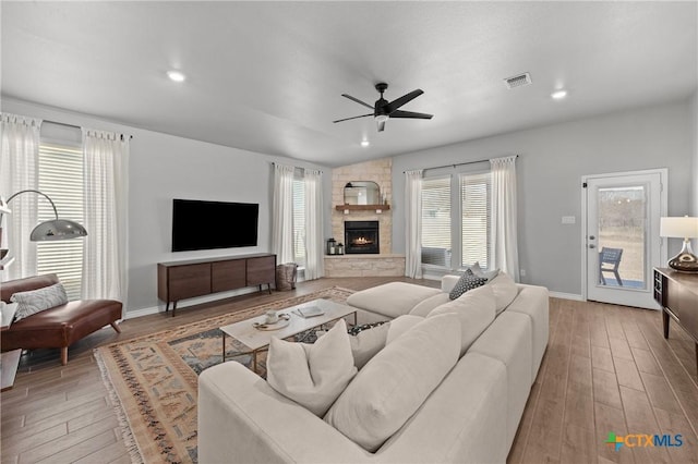 living room with ceiling fan and a stone fireplace