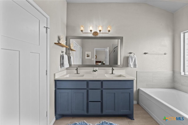 bathroom with vaulted ceiling, a bathtub, vanity, and tile patterned flooring