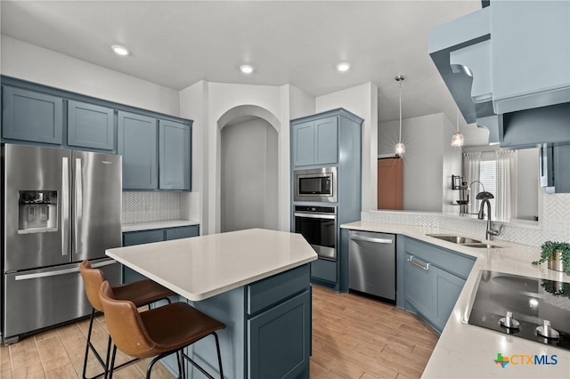 kitchen with stainless steel appliances, tasteful backsplash, blue cabinetry, hanging light fixtures, and sink