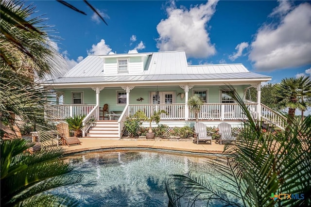 24135 State Highway 172, Port Lavaca, TX 77979 - rear view of house with stairway, a porch, an outdoor pool, and a metal roof