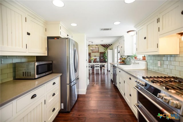 24135 State Highway 172, Port Lavaca, TX 77979 - kitchen featuring appliances with stainless steel finishes, a chandelier, decorative backsplash, dark wood-type flooring, and recessed lighting
