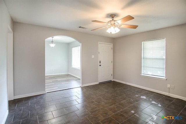 1504 Phyllis Dr, Copperas Cove, TX 76522 - empty room featuring arched walkways, ceiling fan, baseboards, and dark tile patterned flooring