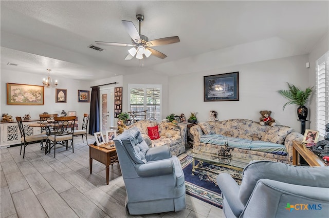 living room featuring ceiling fan with notable chandelier, a textured ceiling, and light wood-type flooring