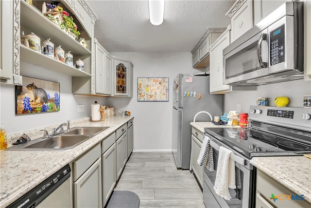 kitchen featuring stainless steel appliances, light hardwood / wood-style floors, sink, a textured ceiling, and gray cabinets