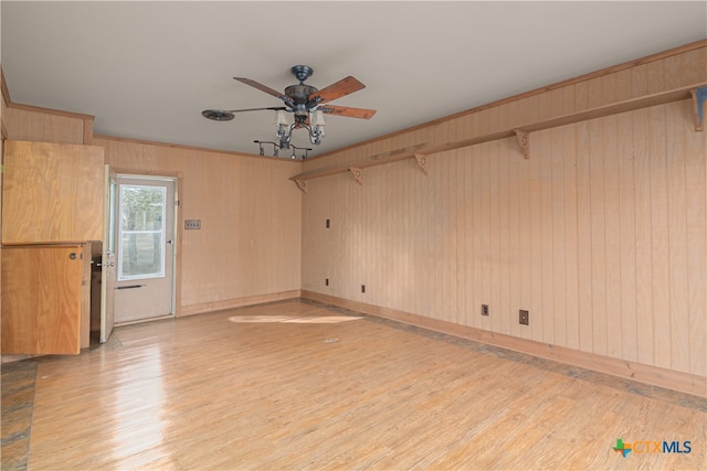 spare room with ceiling fan, wooden walls, and light hardwood / wood-style flooring