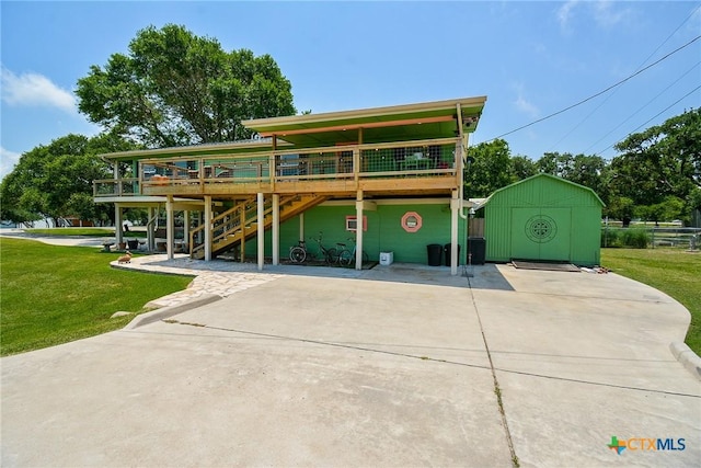 view of front of property featuring a wooden deck, a front yard, and a storage shed