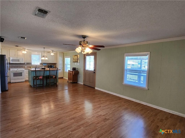 unfurnished living room featuring a textured ceiling, dark hardwood / wood-style flooring, ceiling fan, and ornamental molding