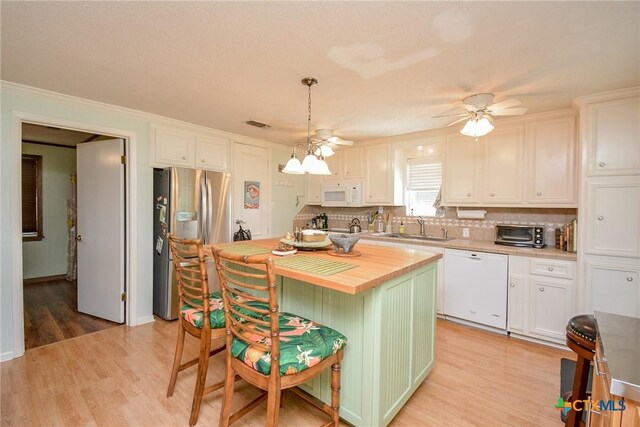 kitchen featuring white appliances, white cabinets, sink, hanging light fixtures, and a kitchen island