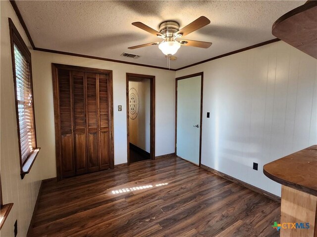 unfurnished bedroom featuring ceiling fan, dark hardwood / wood-style floors, ornamental molding, and a textured ceiling