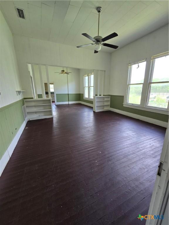 206 Dallas St, Yoakum, TX 77995 - unfurnished living room with dark wood-type flooring, a ceiling fan, and a wainscoted wall