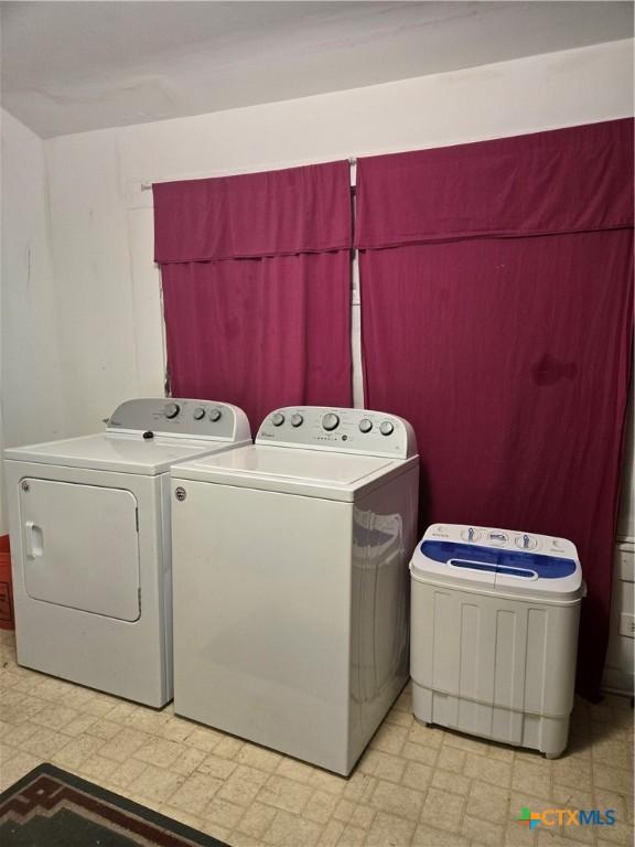 laundry room with laundry area, washing machine and dryer, and light floors